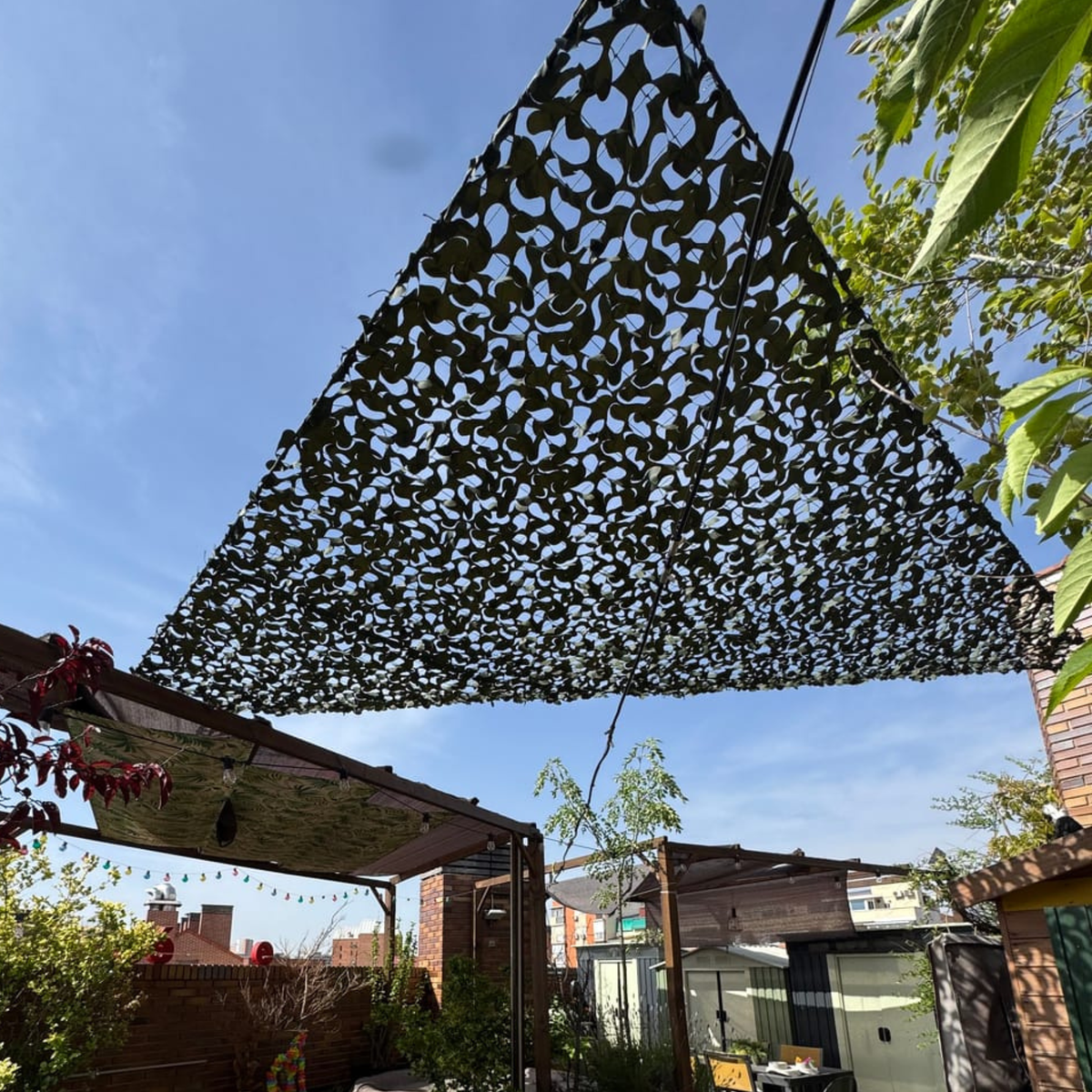 Voile d'ombrage camouflage triangulaire vert installée sur une terrasse