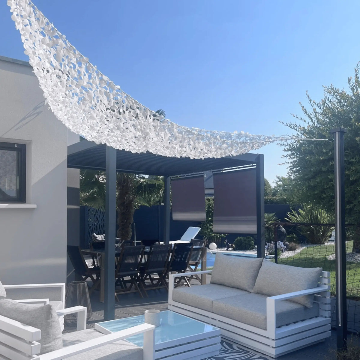 Voile d'ombrage camouflage triangulaire blanc installée sur une terrasse